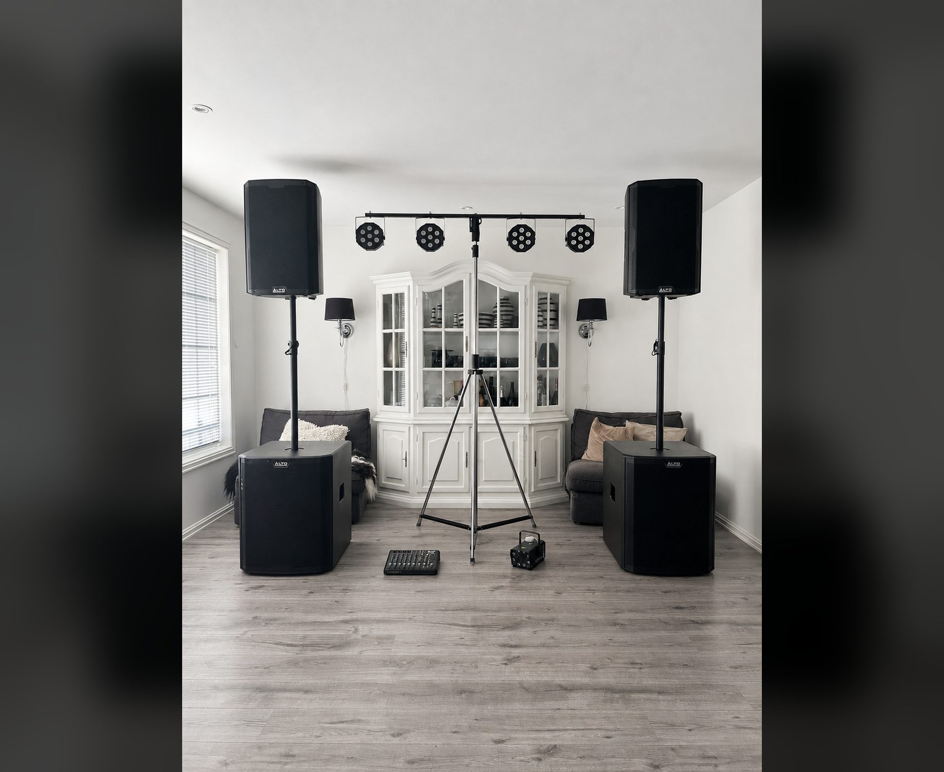 FullRiggen rigget opp i en stue: to høyttalere på hver sin 18 tommers subwoofer, lysbom, mikser og røykmaskin